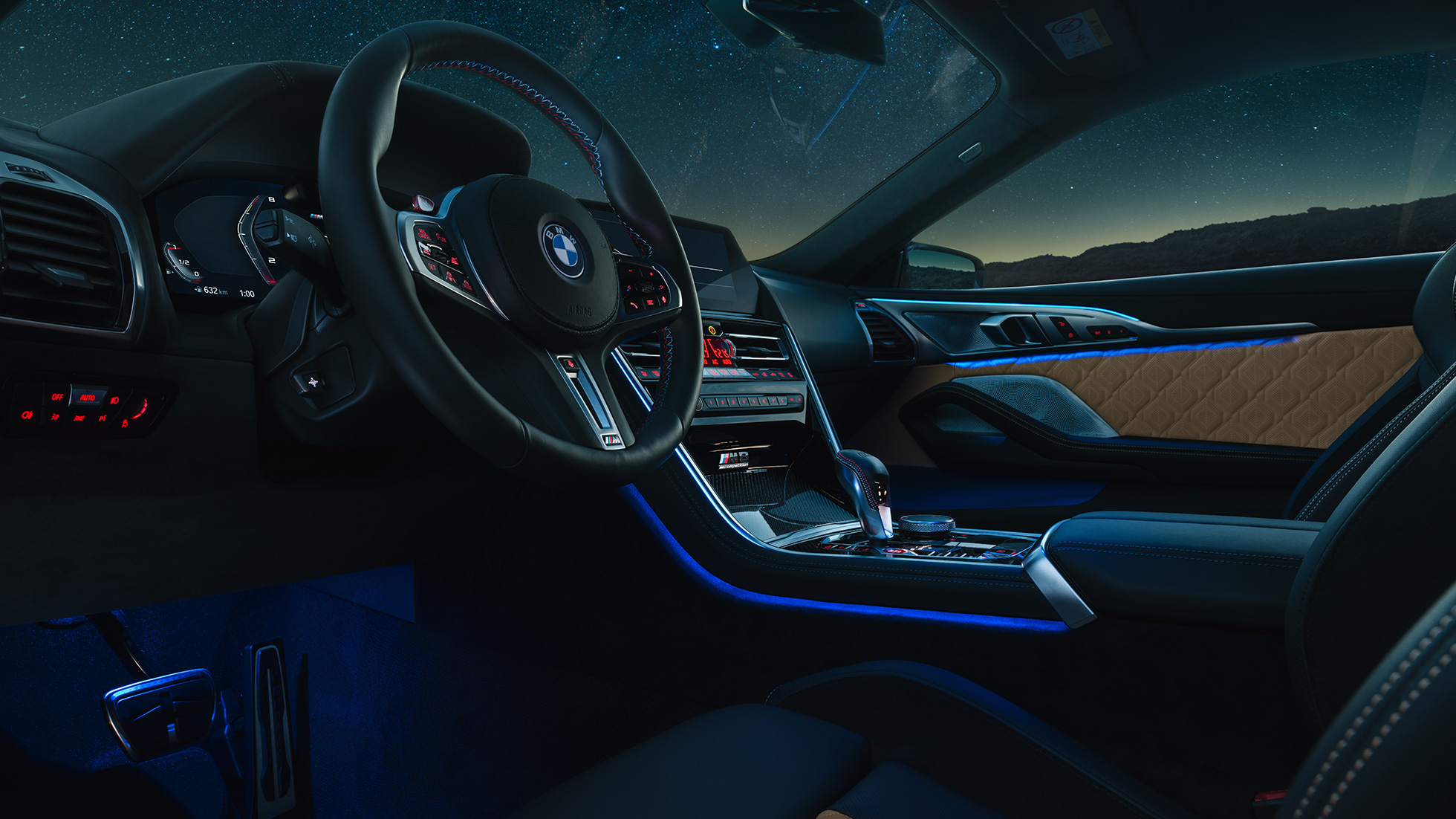 BMW M8 Competition Coupé, cabina. BMW M8 Competition Coupé, cabina de noche con volante de cuero M y luz ambiente azul.