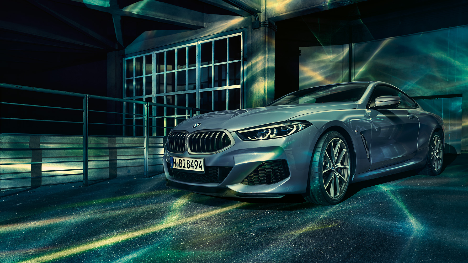 BMW M850i xDrive Coupé, vista frontal tres cuartos. BMW M850i xDrive Coupé en Barcelona Blue metálico, vistra frontal tres cuartos en alto frente a un edificio.
