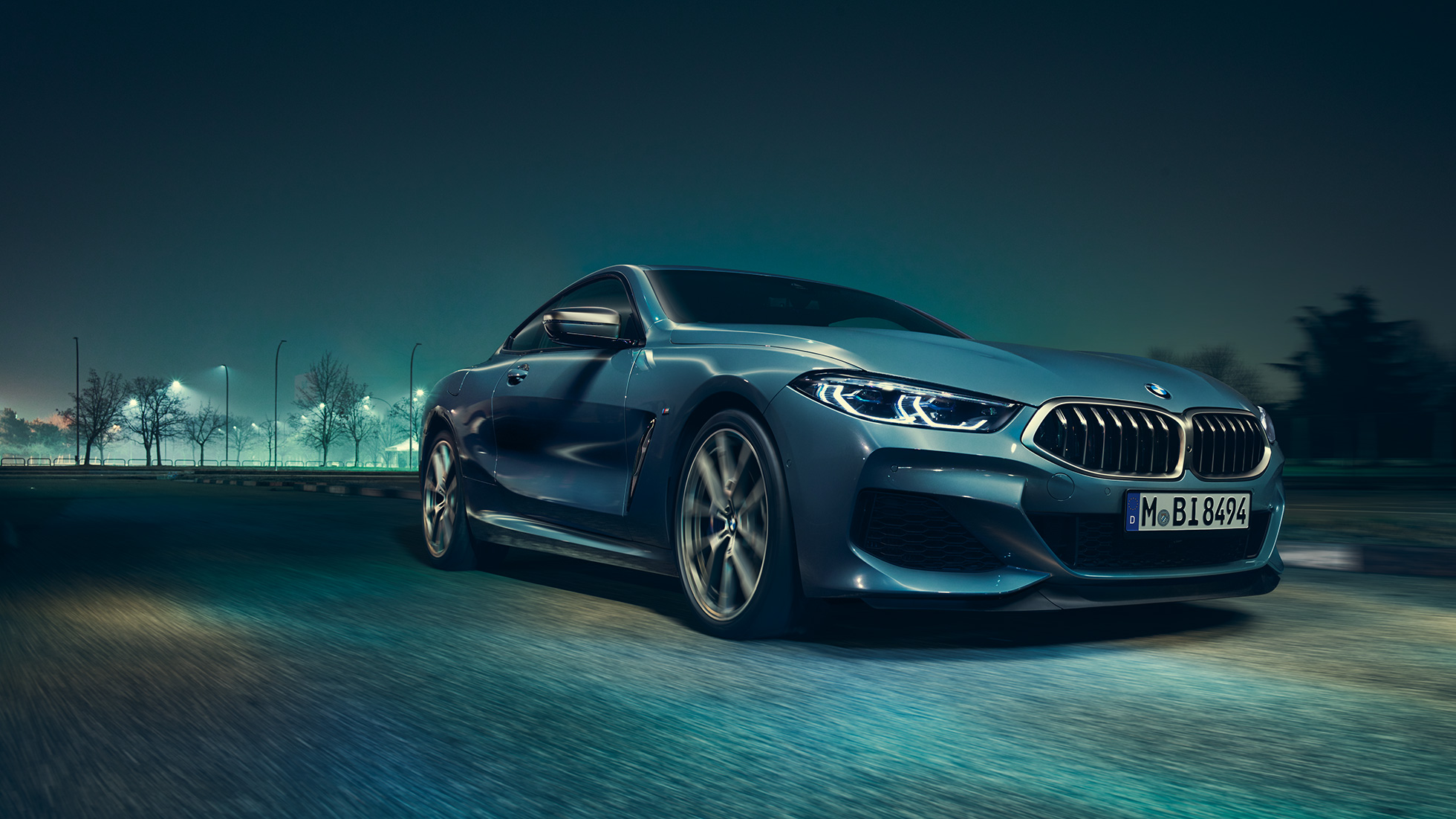 BMW M850i xDrive Coupé, vista frontal izquierda tres cuartos. BMW M850i xDrive Coupé en Barcelona Blue metálico, vista frontal izquierda tres cuartos, conduciendo de noche.