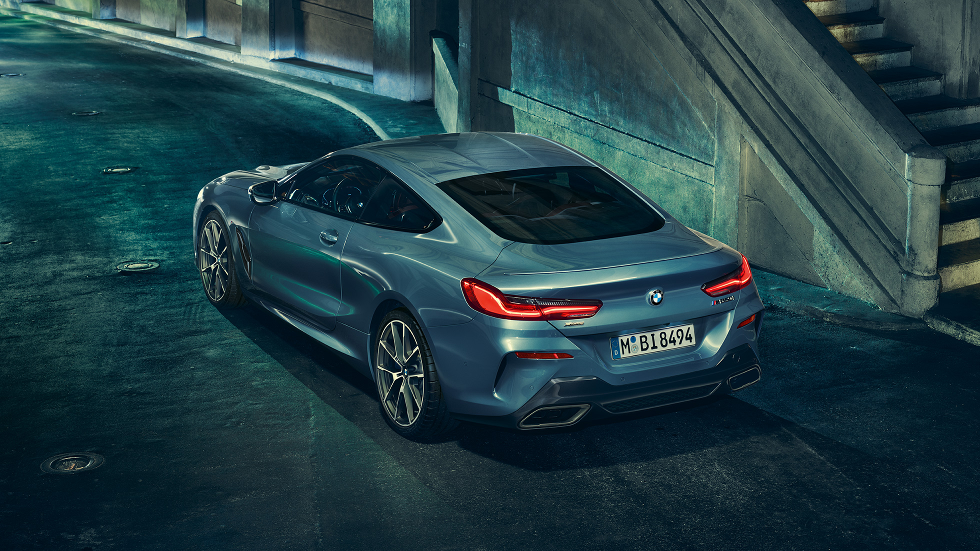 BMW M850i xDrive Coupé, vista posterior izquierda tres cuartos. BMW M850i xDrive Coupé en Barcelona Blue metálico, vista posterior izquierda tres cuartos, en alto de noche.