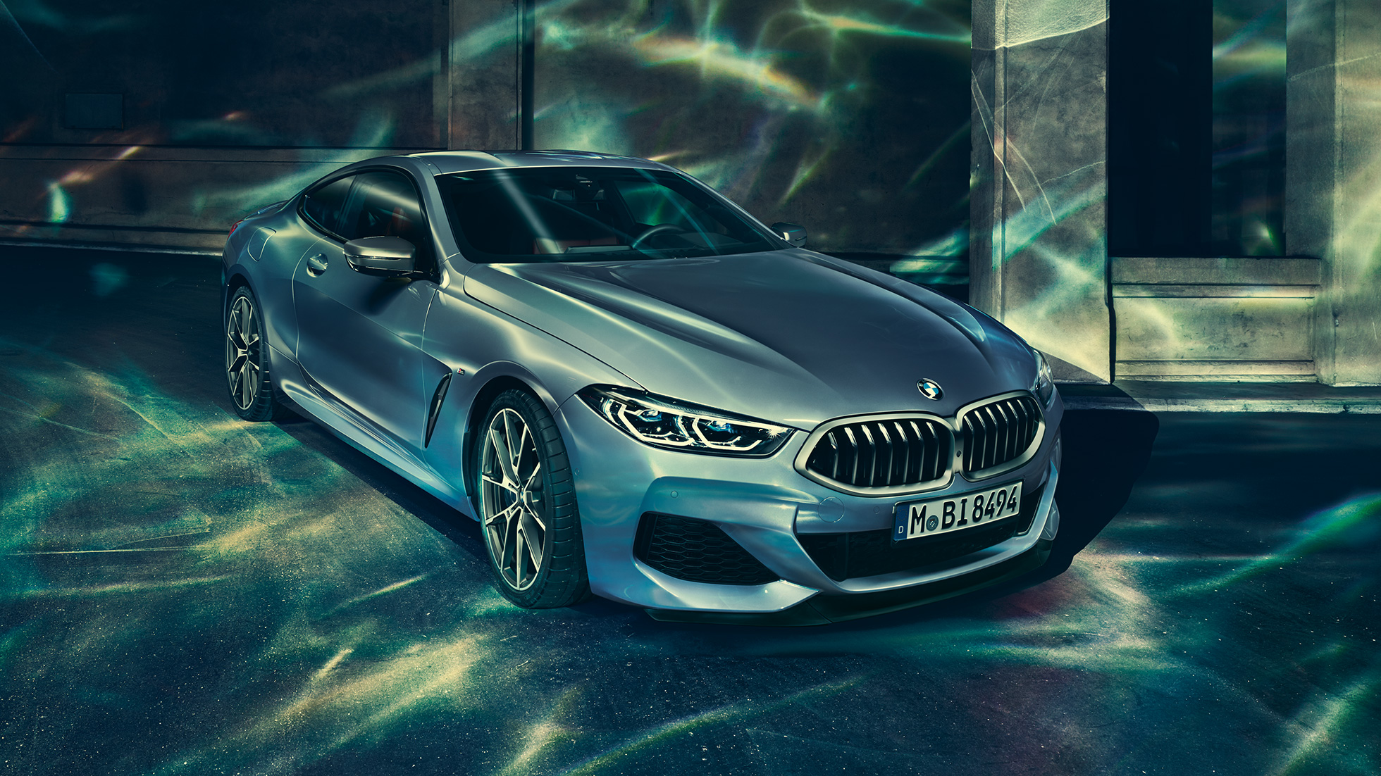 BMW M850i xDrive Coupé, vista frontal izquierda tres cuartos. BMW M850i xDrive Coupé en Barcelona Blue metálico, vista frontal izquierda tres cuartos, parado frente a un edificio.
