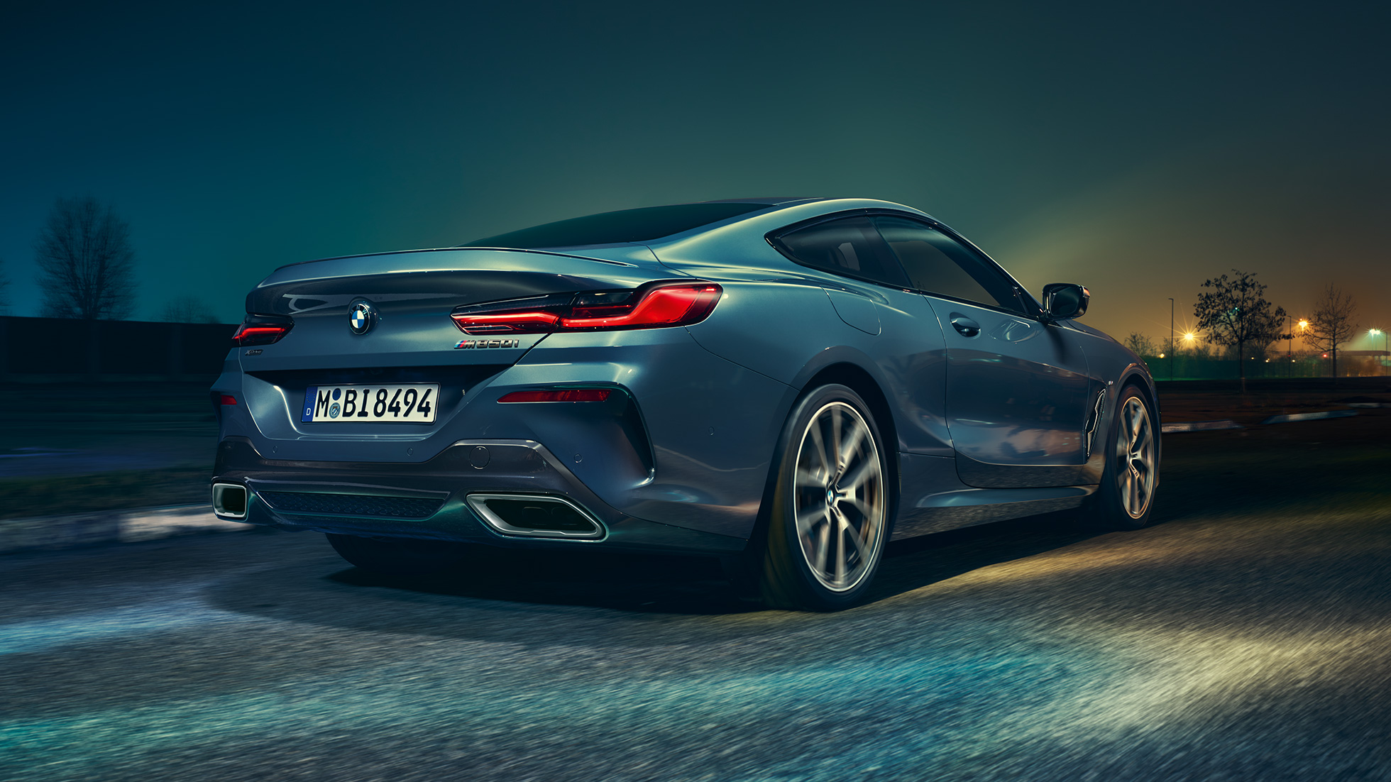 BMW M850i xDrive Coupé, vista trasera. BMW M850i xDrive Coupé en Barcelona Blue metálico, vista trasera, conduciendo de noche.