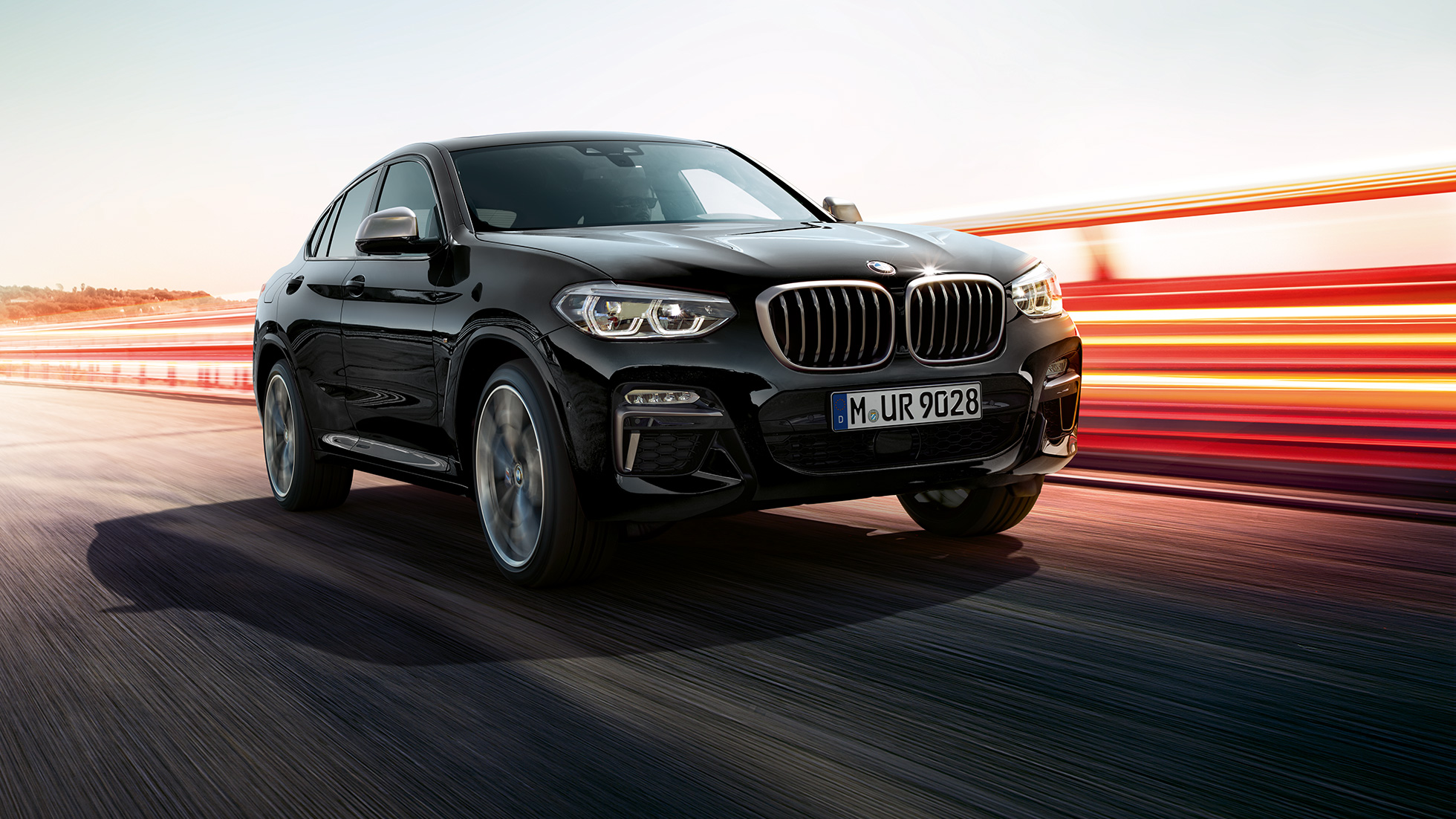 BMW X4 M40i and BMW X4 M40d, three-quarter front view. BMW X4 M40i and BMW X4 M40d in Black Sapphire metallic, exterior, three-quarter front view, left side with light strips.